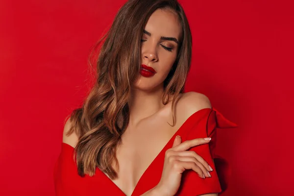 Ternura romântica brilhante mulher elegante com cabelo de ouro ondulado e maquiagem brilhante vestindo vestido vermelho com ombros nus — Fotografia de Stock