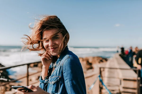 Model yang menyenangkan menikmati pemotretan luar ruangan dengan senyuman. Wanita bahagia mendengarkan musik di pantai laut dan berpose ke kamera — Stok Foto