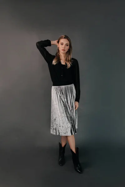 黒のシャツと輝くスカートを身に着けているエレガントなスタイリッシュなブロンドの女性のフルレンズファッションの肖像画は、暗い背景の上にポーズ — ストック写真