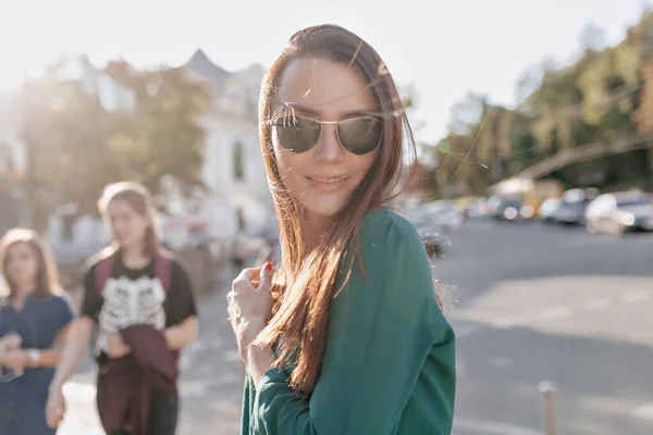 Adorable mujer encantadora con sonrisa feliz caminando bajo el sol en la ciudad y disfrutando de un buen día cálido — Foto de Stock