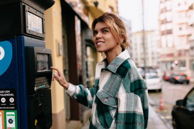 Koleksiyonlu sarı saçlı, çizgili gömlek giyen, park ücretini ödeyen güzel bir kız.