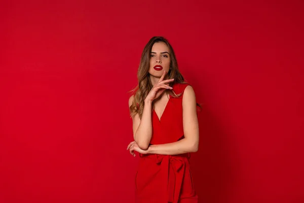 Estudio disparo de la mujer encantadora de moda en vestido rojo posando sobre fondo rojo aislado — Foto de Stock