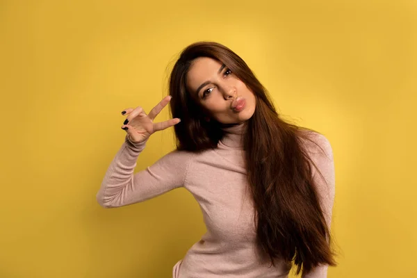 Funny lovable woman showing peace sign and posing over isolated yellow background. — 스톡 사진