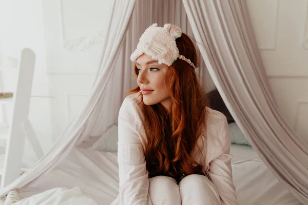 Feliz hermosa mujer con el pelo largo se despertó en la mañana. Imagen de la joven sonriente bella dama yace en la cama en el interior . —  Fotos de Stock