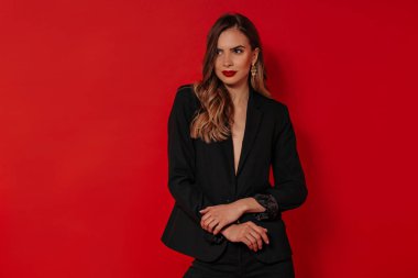 Beautiful woman with evening make up wearing black jacket posing over isolated red background. Birthday, Valentines day, holiday