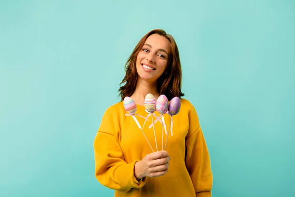 Charming pretty lady in bright clothes posing with Easter eggs over bright background. Preparing for Holiday. Easter celebration.