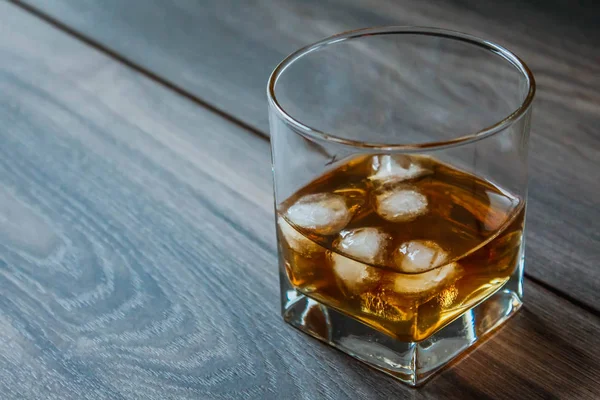 木製の背景にウイスキーと氷のキューブとガラス — ストック写真
