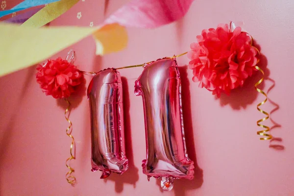 Doğum günü balonları numarası. 11 'inci yaş günü. Balonlu ve kurdeleli pembe duvar.
