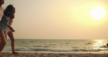 Ağır çekim: Kadın arkadaşlar günbatımında hayatın tadını çıkarıyorlar ve özgürlük plajında arkadaşlarıyla birlikte Asyalı kadın gezginlerin yaşam tarzlarını çekici buluyorlar. 4k Uhd.