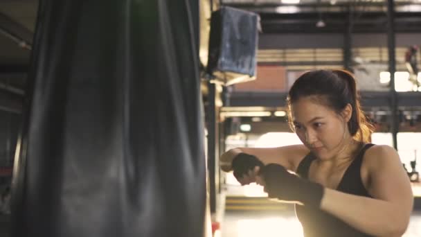 フィットネスジムの健康的なライフスタイルで彼女の練習ボクシングパンチングバッグと女性のトレーニングキックボクシングの練習 アスレチックスポーツトレーニング持久力の強いワークアウト スローモーション映像映画 — ストック動画