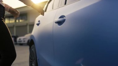 Tilt shot, kadın sistemlerinin eli yavaş çekimde araba sürmeden önce kapının kilidini açar, mavi hatchback aracının sokak yolunda araç yolculuğu. Sinematik görüntüler 