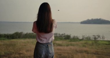 Gezgin genç Asyalı kadın günbatımında Orman Dağı nehri gölünde film kamerasıyla fotoğraf çekiyor, açık havada iyi yolculuklar. Süper yavaş çekim C4k Sinematik kamera görüntüleri