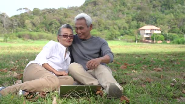 アジアのカップルシニア退職リラックスし フロントハウスの家族でラップトップコンピュータ技術を見て一緒に幸福の人々のライフスタイル スローモーション映像 — ストック動画