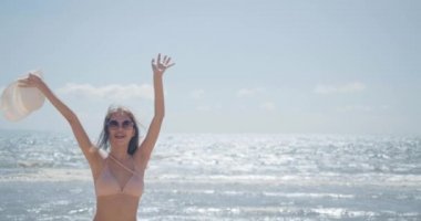 SLOW MOTION: Smiling Young bikini sexy asian woman playing freedom at seaside beach tropical resting and relaxation travel lifestyle concept