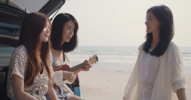 在海滩暑假的时候 年轻的亚洲女人在后备箱 公路旅行 周末旅行 开车旅行中 一起弹奏着 Ukulele 的歌曲 — 图库视频影像