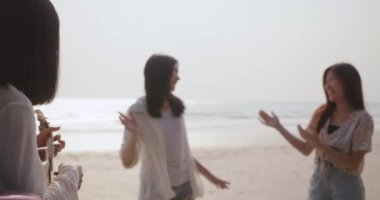 Gülümseyen Mutlu Arkadaşlar genç Asyalı kadın grubu dansları, plaj tatilinde ukulele şarkıları çalmaları, bagaj hatchback araba yolculukları ve seyahat hafta sonları, araba konseptiyle yolculuk etmeleri.