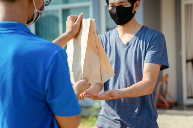 Maske takan Asyalı Teslimatçı restoran koruma salgınından yiyecek ve yüksek ateş yolluyor. Virüs yayılırken kargo sevkiyatına sosyal mesafe koyuyorlar..