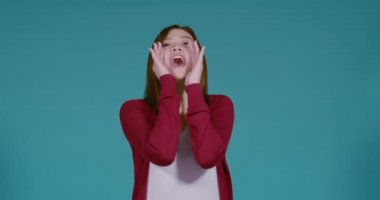 Genç Asyalı bir kadın çığlık çığlığa bağırıyor. Mavi arka planda, sargı beziyle yüksek sesle konuşuyor. İzole edilmiş stüdyo çekimi..