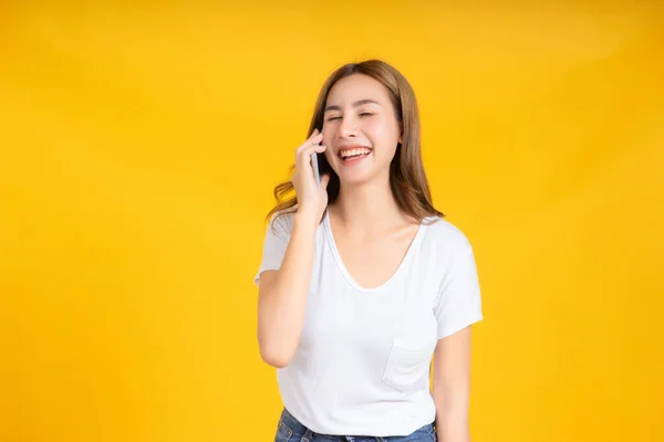 아시아인 스마트폰으로 대화하는 티셔츠를 긍정적 노란색 고립된 스튜디오 — 스톡 사진