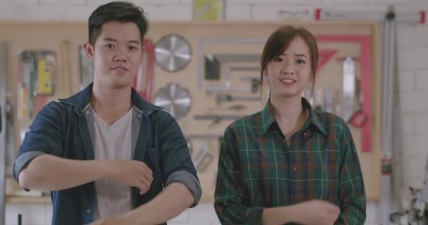 労働者の若いアジアのカップルの男性と女性の大工は ワークショップオフィススタジオ 個人的なビジネスコンセプト スローモーションで腕の笑顔の建物のデザイン木製の作業を渡った — ストック動画