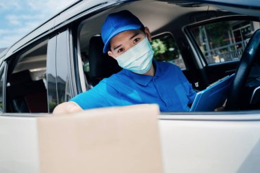 Maske takan Asyalı kurye paketi alıp kargo teslimatına götürüyor ve virüs karantinaya alınırken arabada bir sürü paket var..