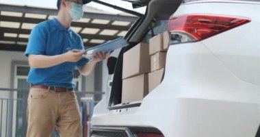 Maskeli bir teslimatçı, teslimat sırasında paketi alıp kargo sosyal mesafesini belirliyor ve virüs günbatımında yayılırken bir çok paket de bagaj vagonunda..