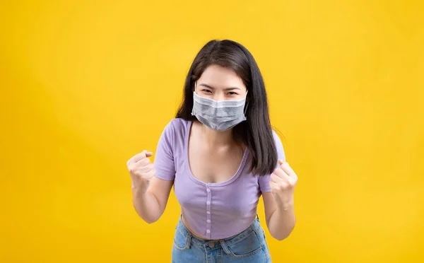 工作室拍摄了头戴口罩的亚洲妇女的肖像 以防止感染 并在黄色背景的眼镜蛇19病康复后高兴地激动起来 — 图库照片