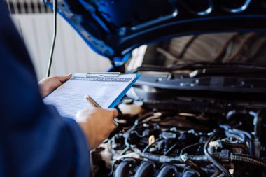 Tamirci, sigorta sistemiyle motoru tamir ediyor. Araç kaputu, müşteri uzun bir yolculuğa çıkmadan önce güvenlik denetimi, ulaşım onarım garaj servisi.