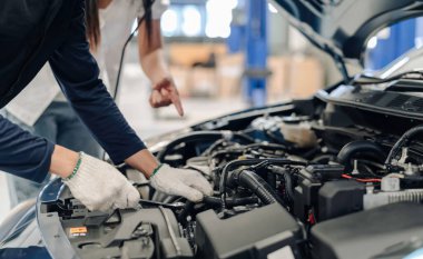 Mekanik Asyalı adam müşteriyi muayene ediyor ve kontrol ediyor. Araç kaputu, güvenlik denetimi motoru. Müşteri uzun bir yolculuğa çıkmadan önce, ulaşım onarımı.