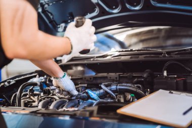 Tamirci müşteriyi muayene ediyor ve kontrol ediyor. Araç kaputu, güvenlik denetimi motoru. Müşteri uzun bir yolculuğa çıkmadan önce, ulaşım onarım servisi.