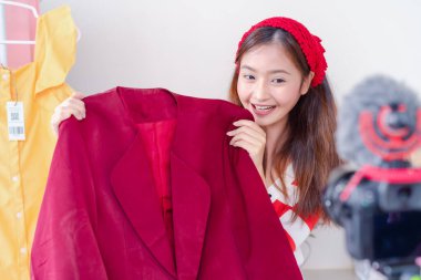 Güzel Asyalı genç kadın vlogger blog sunumu giysi moda videosu canlı sosyal medya dijital kamera ile satışını kaydediyor.