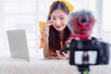 Güzellik blogcusu genç Asyalı kadın makyaj malzemesi sunumu. Cilt makyajı videosu dijital kamera ile çevrimiçi olarak kaydediliyor. Vlogger 'ın küçük işletme girişimcisi insan yaşam tarzı.