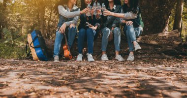 Bir grup Asyalı genç kadın, kampa gitmek üzere tatil zamanından önce yolculuk arasında su içiyorlar..