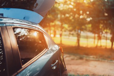 Gün batımında ormanda seyahat etmek için Hatchback 'in sıcak arabasının park yeri tatil ve yaz konsepti..