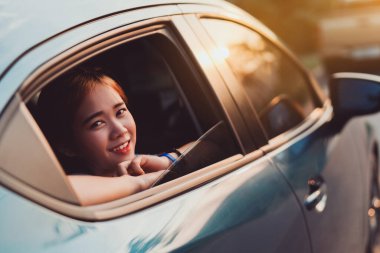 Hatchback araba yolculuğu Asyalı bir kadının yaz tatilini gün batımında mavi bir arabayla sürmesi kızlar tatilin ve arkadaşlarla dinlenmenin keyfini çıkarması atmosferi oluşturur.