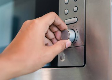 Döndürme tutan el daire düğmesi ısı odasında Gıda Mutfak Ev, Closeup yemek pişirmek için mikrodalga fırın çevir.
