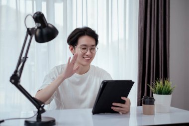 Riski, karantinayı, koronavirüsü, covid-19 'u azaltmak ve e-learing online eğitim teknolojisi kavramını öğrenmek için evden tabletle kendini toplumdan izole eden Asyalı bir adam..