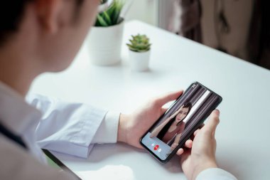 Tıbbi Coronavirüs video arayüzü kullanıcı arayüzü arayüzü için kadın hasta bakımı danışmanı ve danışmanı ile Asyalı doktor video konferansı evde karantinadayken çevrimiçi sağlık hizmetleri uzaktan konuşuyor.