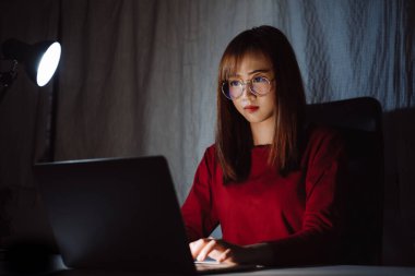 Gece geç saatlere kadar bilgisayar başında çalışan Asyalı bir kadın ekran monitörüne bakıp mutsuz, uykusuz, serbest çalışan bir kadın karanlık odada iş karantinası krizi Coronavirüs 'ünde kalıyor..