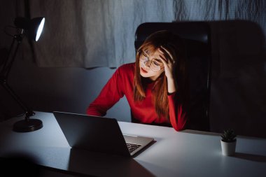 Gece geç saatlere kadar bilgisayar başında çalışan Asyalı bir kadın ekran monitörüne bakıp mutsuz, uykusuz, serbest çalışan bir kadın karanlık odada iş karantinası krizi Coronavirüs 'ünde kalıyor..