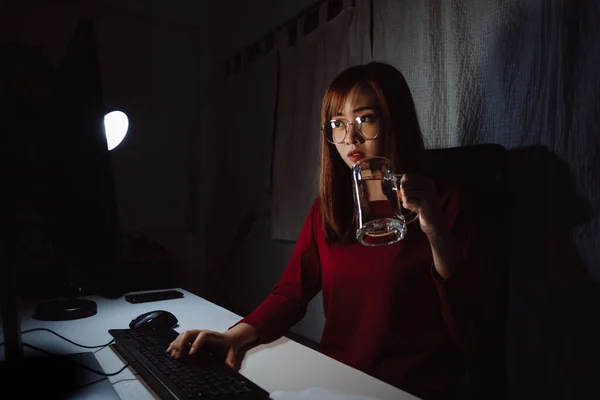 Korean woman working late time with laptop computer drinking water home office workhard overworked, Freelancer stay home business quarantine sleepless crisis coronavirus stay home dark room