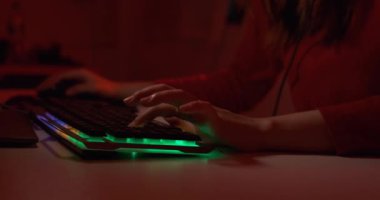 Profesyonel oyuncu genç Asyalı kadın çevrimiçi video oyunu oynuyor FPS turnuvası vuruyor gece kırmızı neon ışık odasında internet sıralaması yapıyor oyun kulaklığı ve klavye ile şampiyonluk etkinliğinde.