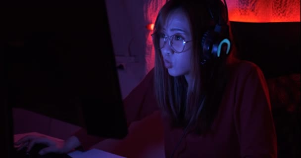 プロゲーマーの若いアジアの女性がオンラインビデオゲームのシューティングFpsトーナメントのランキングサイバーインターネット夜の赤ネオンライトルームでゲームでチャンピオンシップイベントのハンドヘルドショット4K Uhd — ストック動画