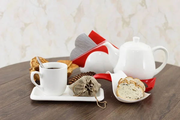 tea kettle with tea cup and pastry sweets on dark wooden table background