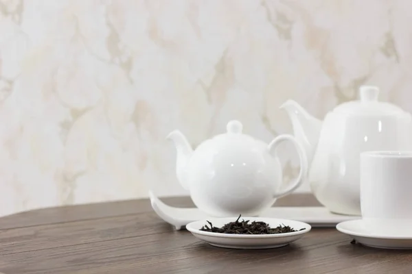 white tea kettles with tea cup and dried leaves on wooden table background