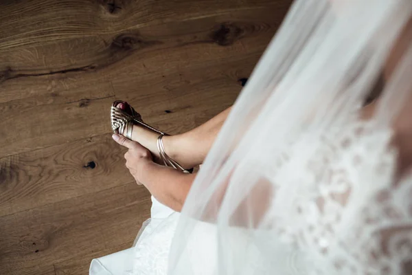 Elegant Female puts hands on wedding shoes on a background white dress, Wedding morning preparation in home. — Stock Photo, Image