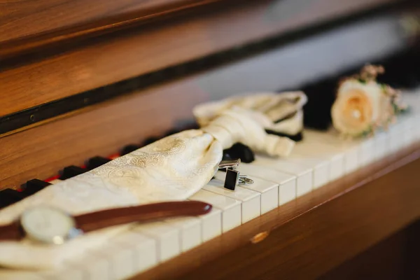 グルームのアクセサリーだピアノの鍵にスタイリッシュな時計、ネクタイ、ボトニエールとカフスボタン。新郎の朝. — ストック写真
