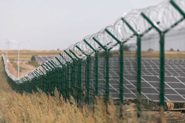 Сонячна електростанція захищена від дороги колючим дротом. Огорожа чутливих ділянок з колючим дротом . — стокове фото