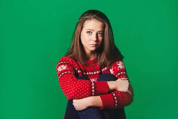Молода жінка в новорічному светрі на зеленому тлі — стокове фото