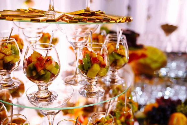 Färska, exotiska, ekologiska frukter, lätta snacks i en tallrik på ett buffébord. Blandade minidelikatesser och snacks, restaurangmat på evenemanget. Dekorerat läckert bord för en fest godsaker. — Stockfoto